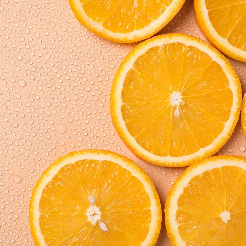 orange slices on a peach colored background with water droplets