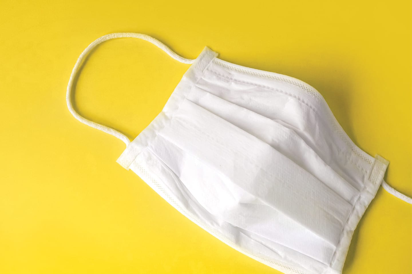 Disposable Face Mask on a Yellow Background