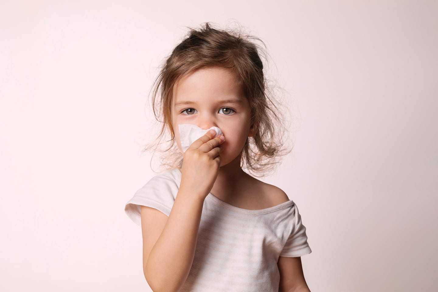 Toddler little girl blowing her nose with a tissue