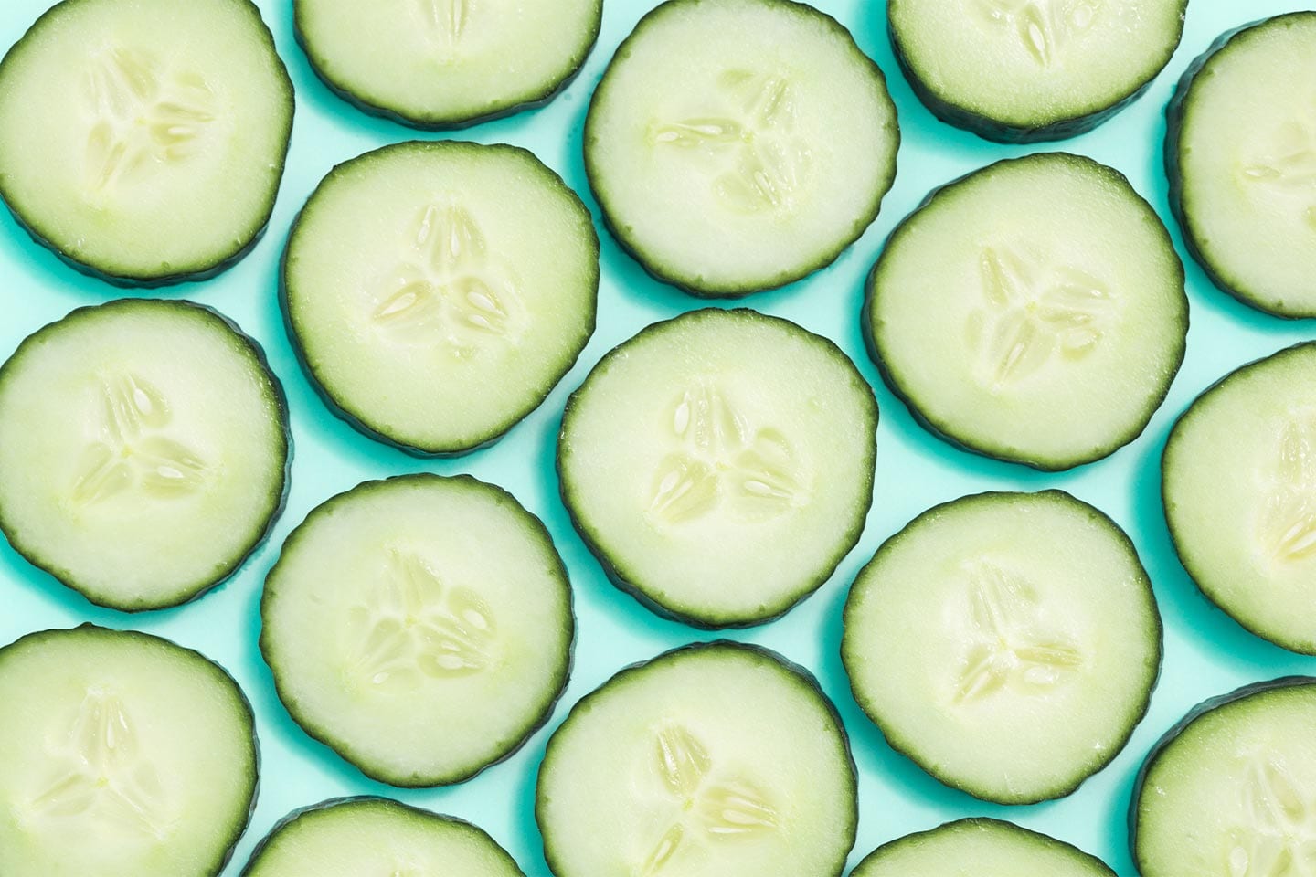 cucumber slices on a mint green background