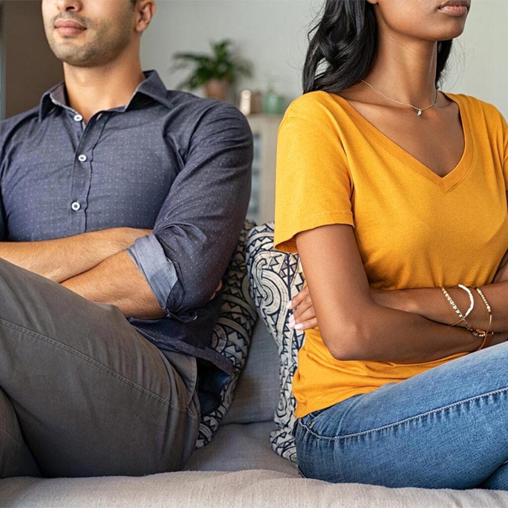 Arguing couple in a toxic relationship with backs turned to each other on a sofa