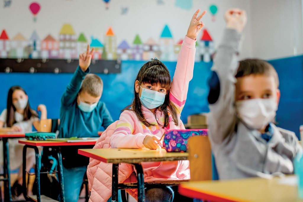 elementary school children in person in the classroom wearing masks