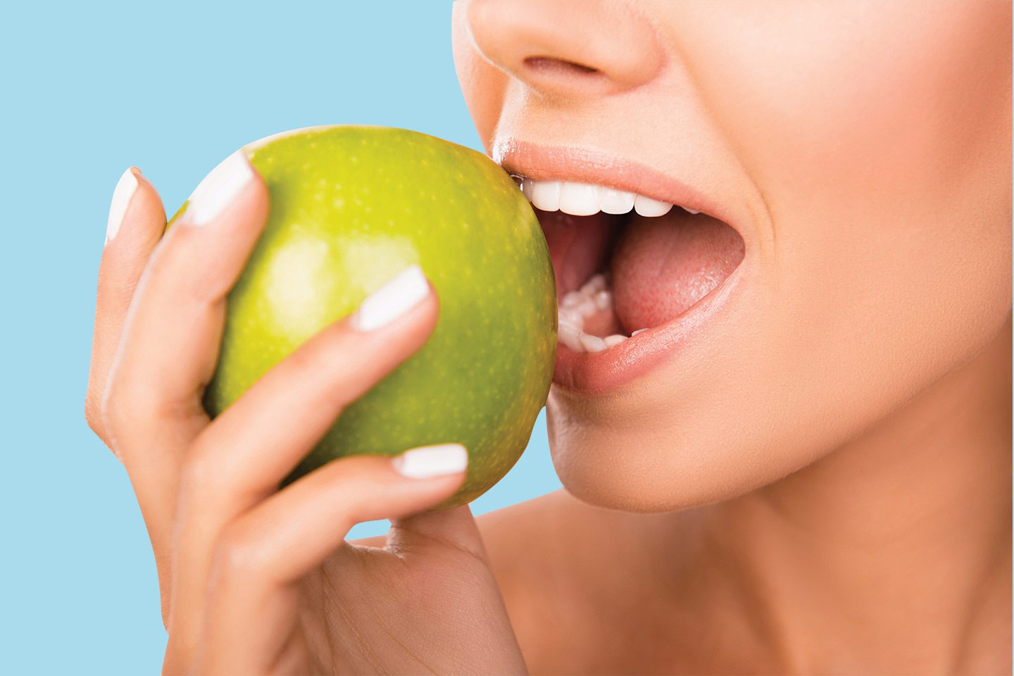 woman with healthy teeth eating an apple