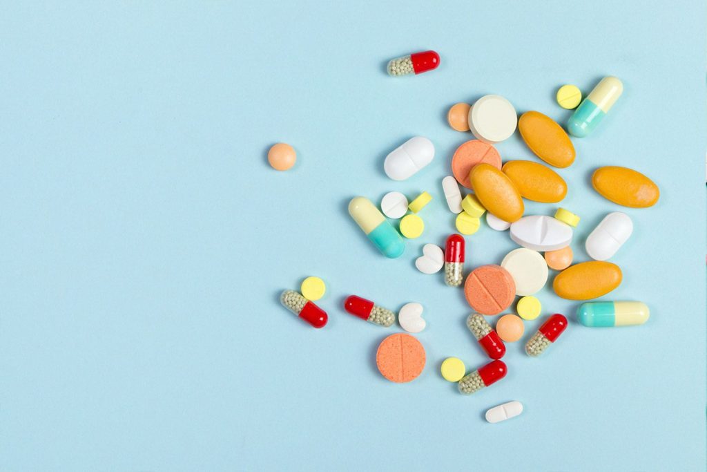 pile of colorful pills on a light blue background