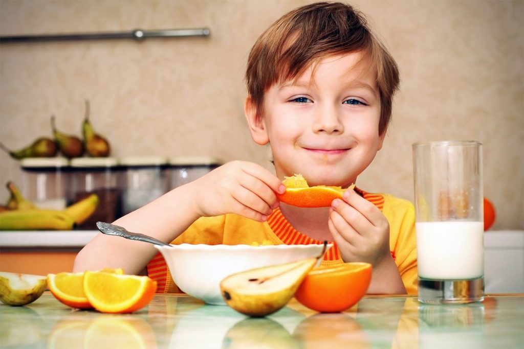 little boy eating an orange slice