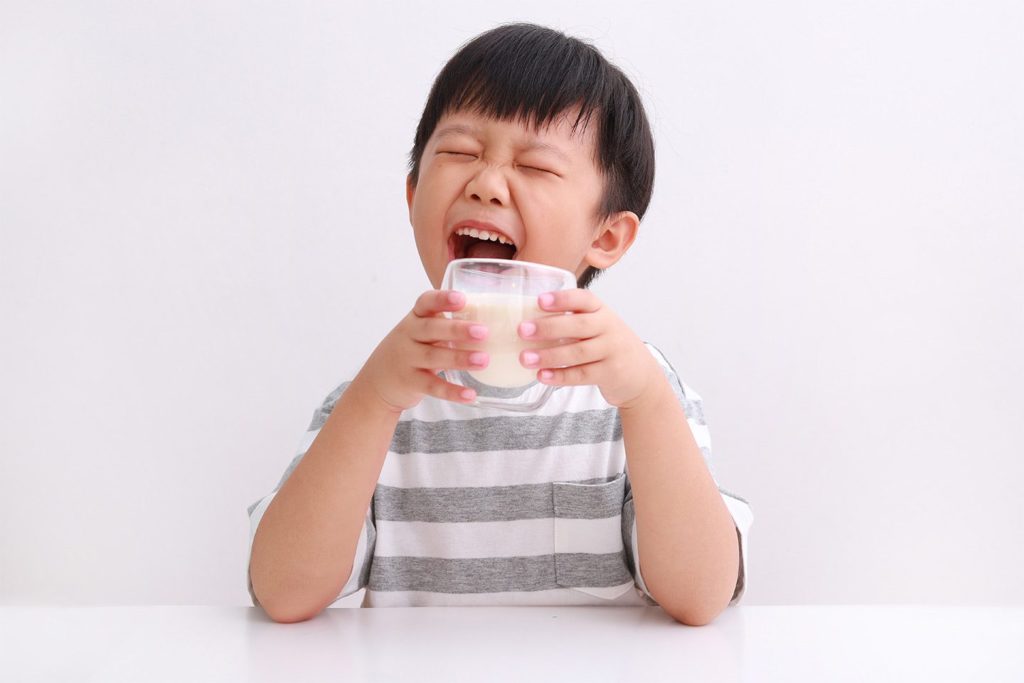 little boy drinking a glass of milk