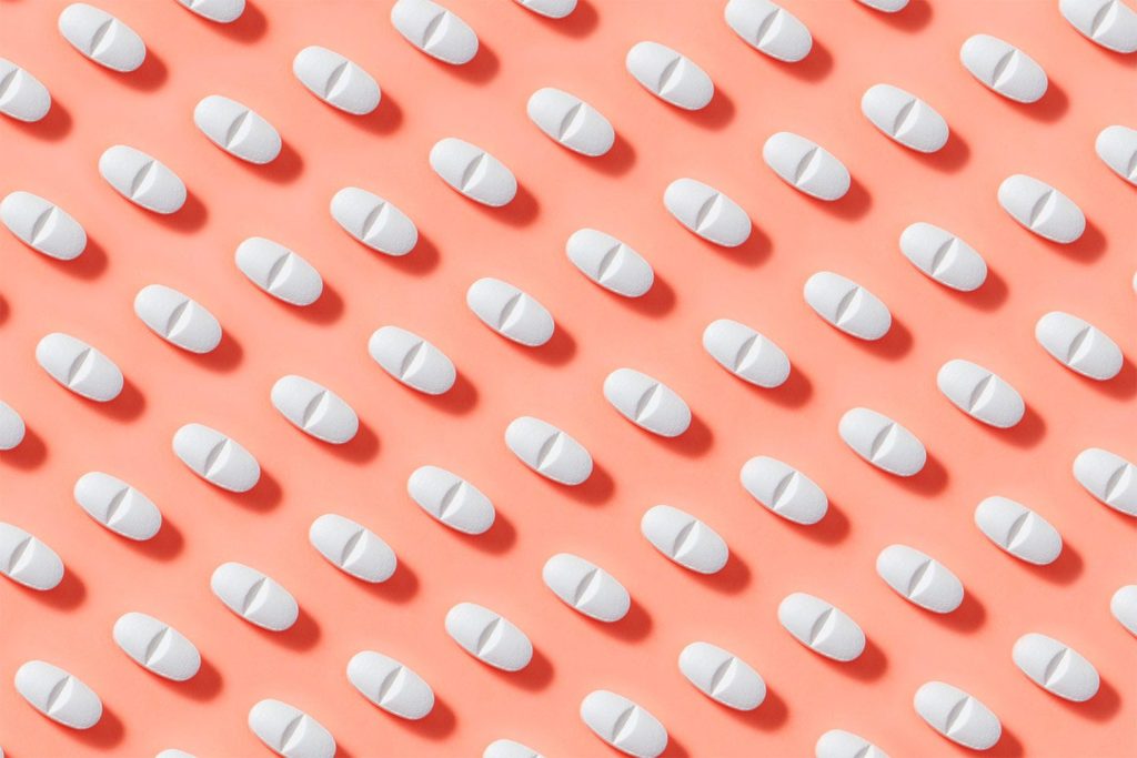 white pills on a coral background