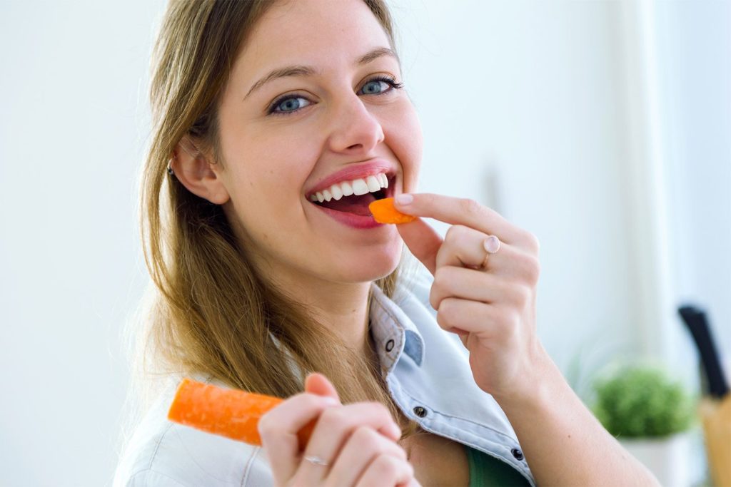 happy woman eating a carrot