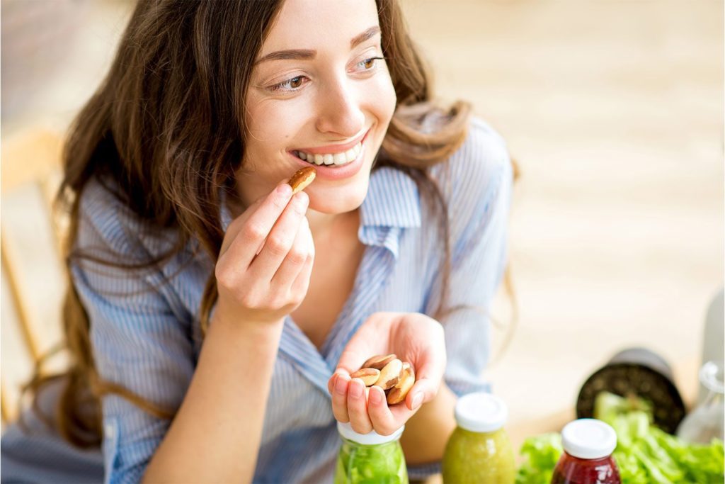 smiling woman eating a handful of nuts