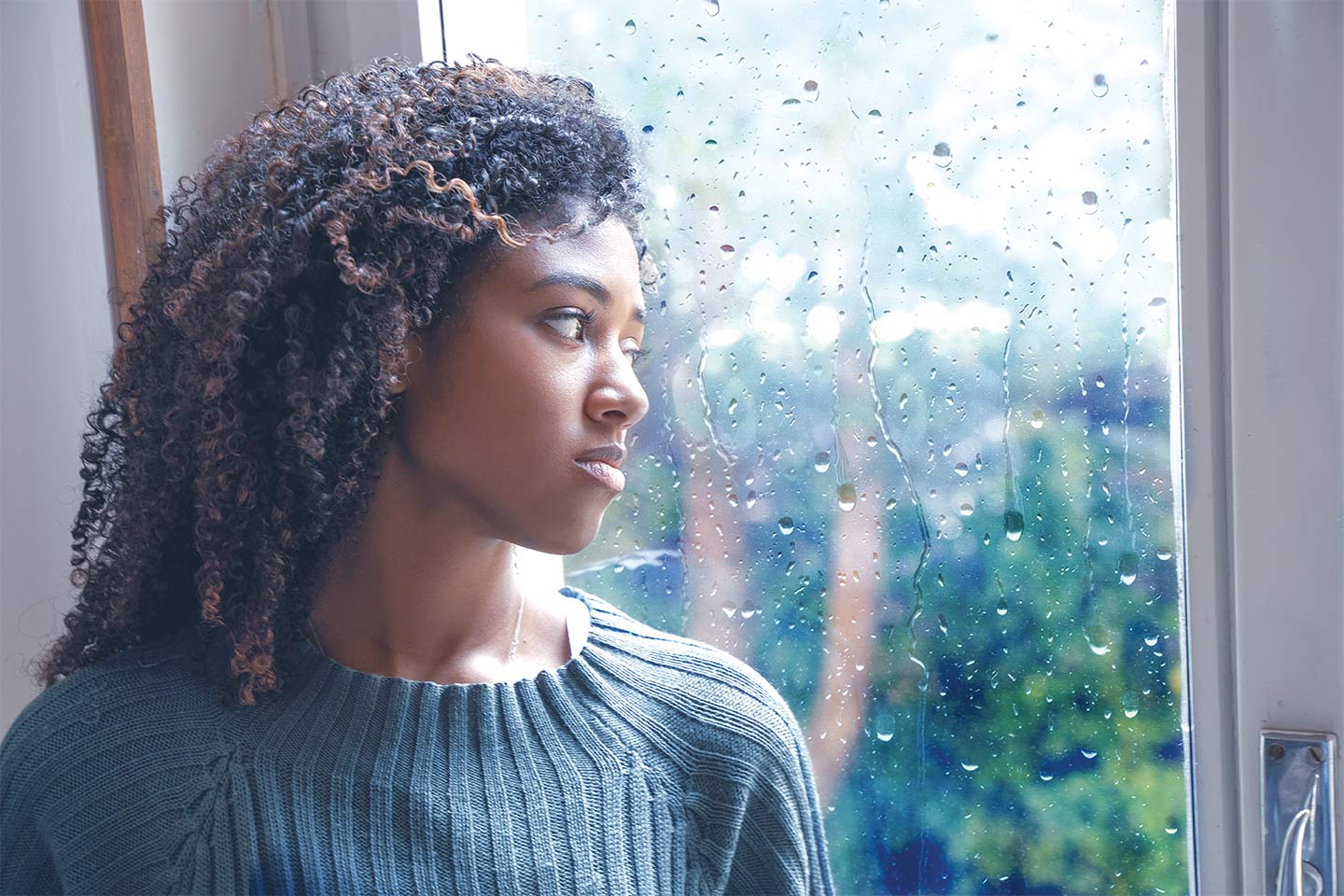 depressed woman looking out the window at the rain