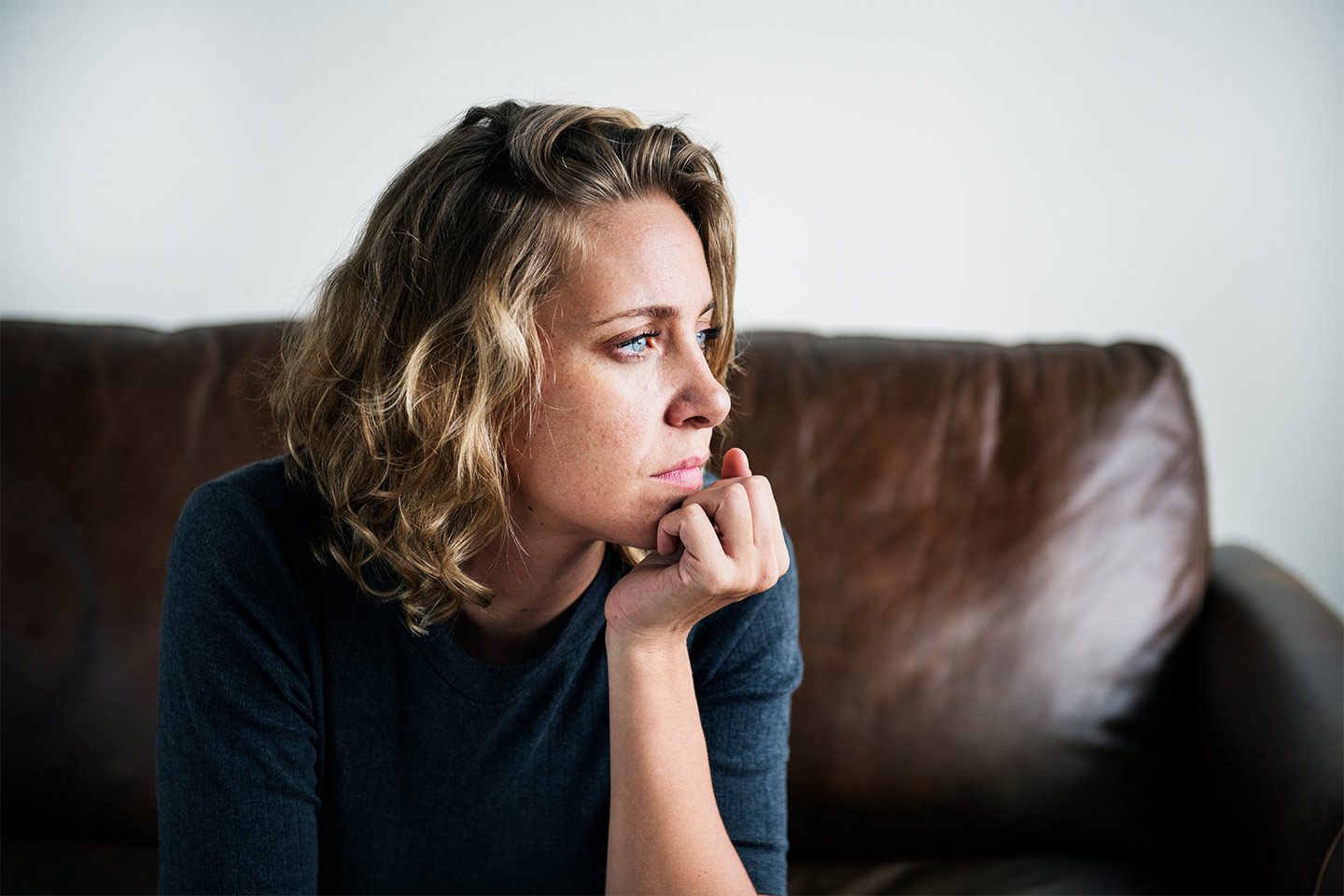 Woman sitting on couch looking anxious and depressed