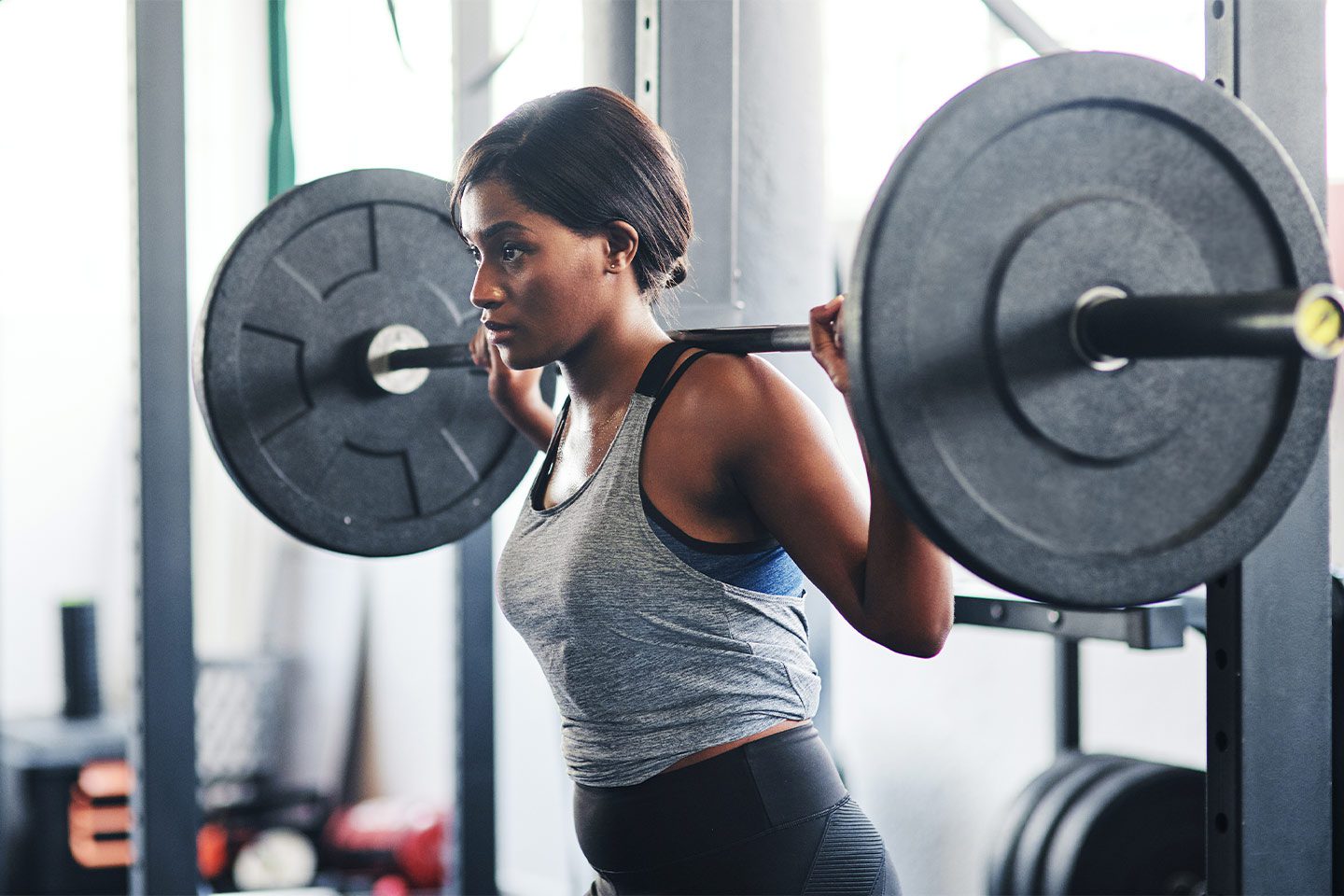 Woman doing squats with a barbell at the gym