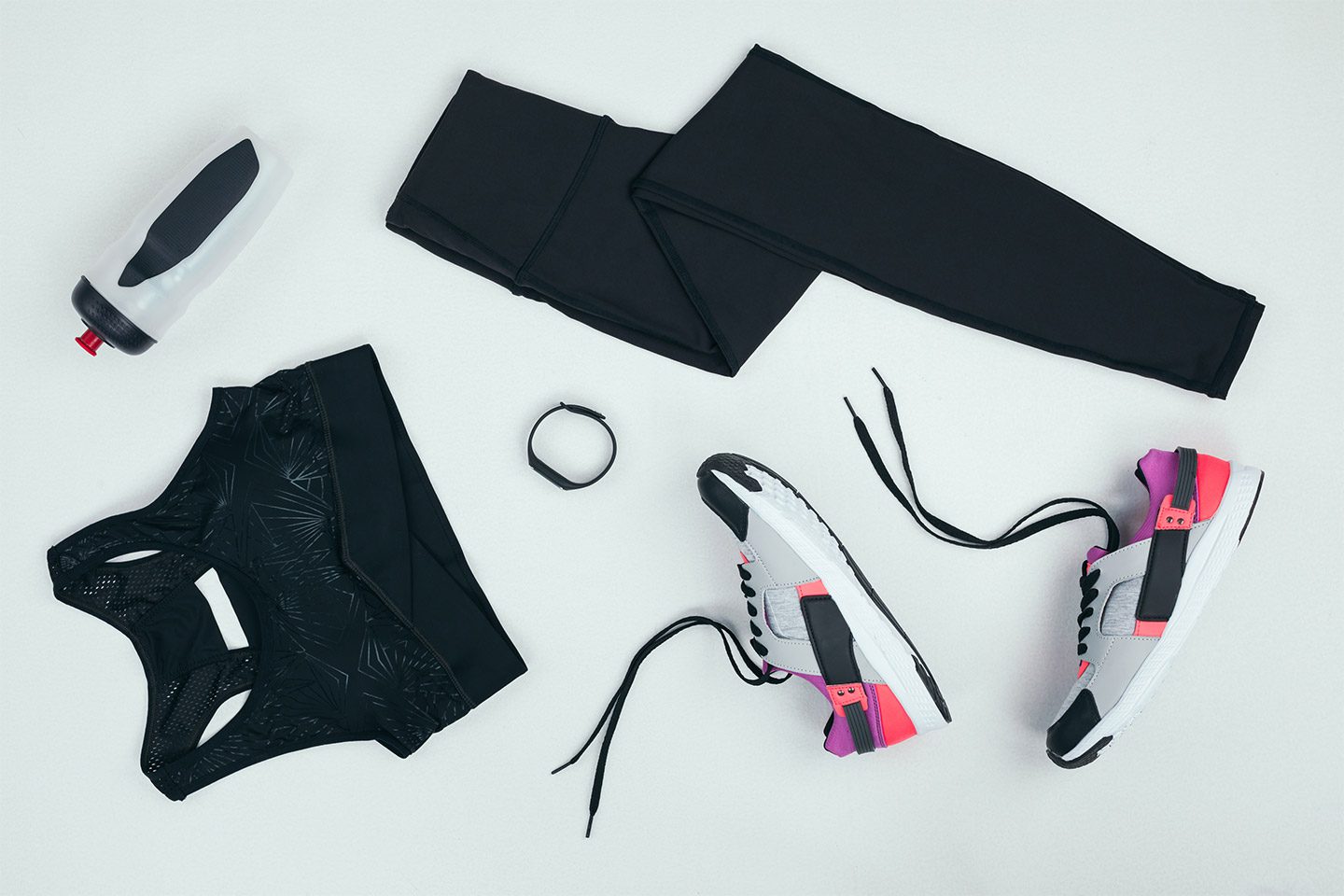 flat lay of exercise clothes, a fitness tracker, and a water bottle