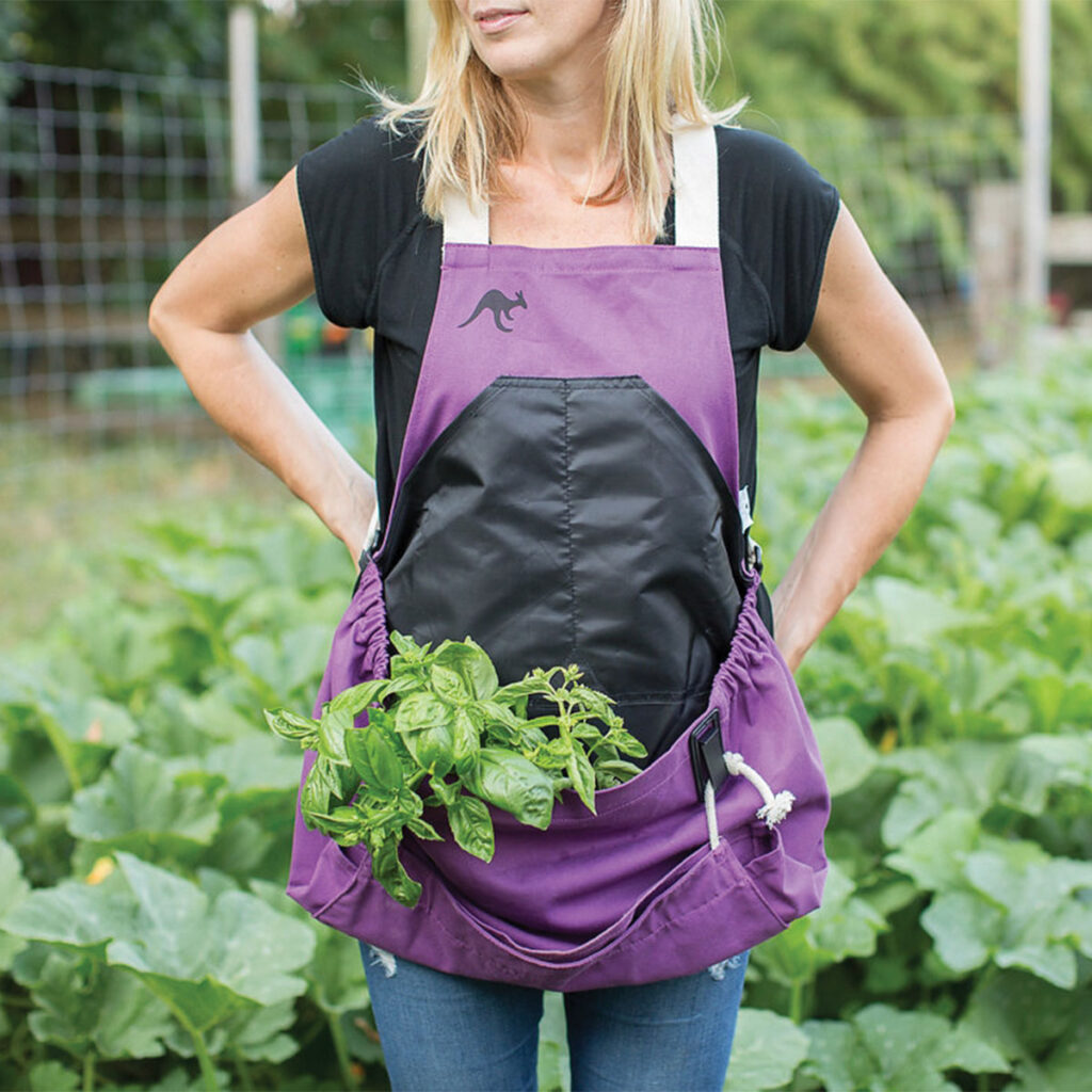 woman wearing a gardening apron with a pocket holding a plant