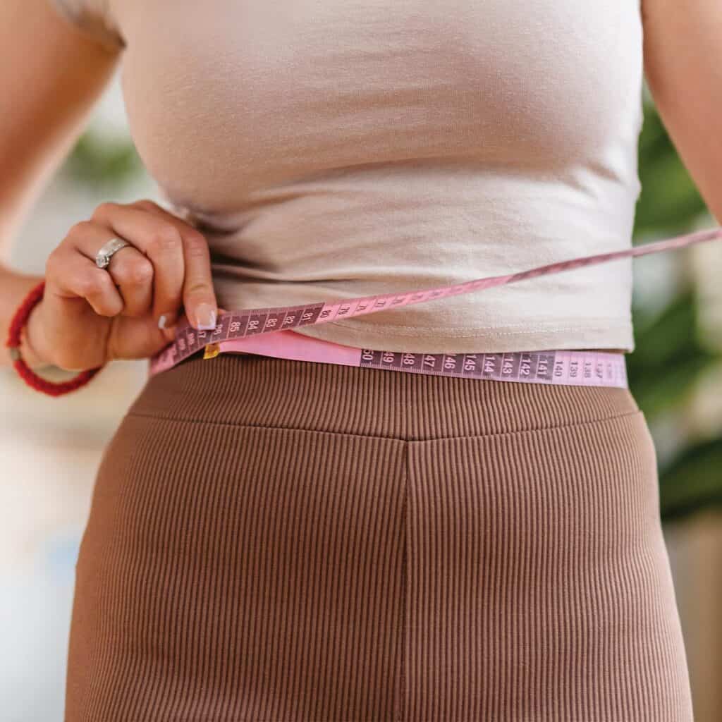 woman measuring her waist line