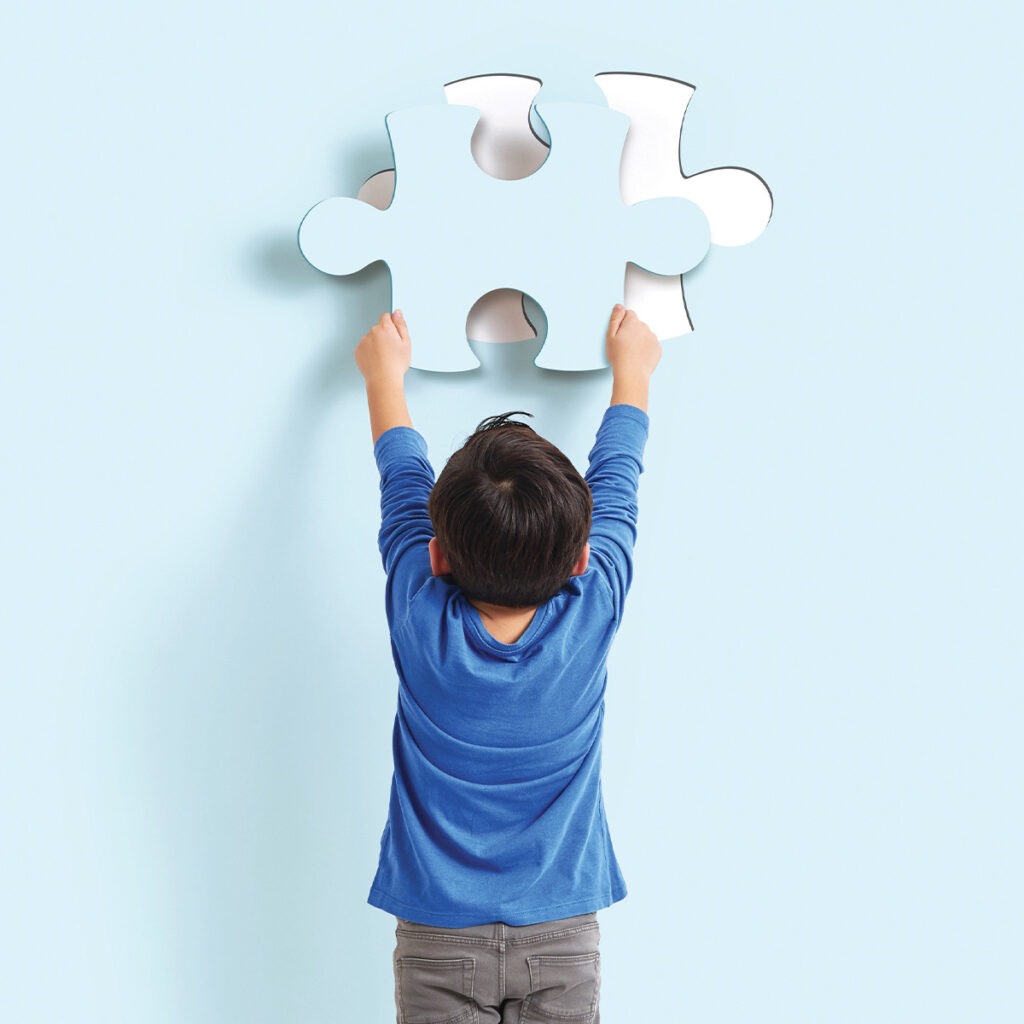 child placing a large puzzle piece onto wall