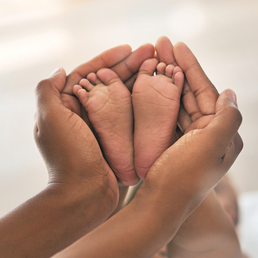adult holding infant baby's feet
