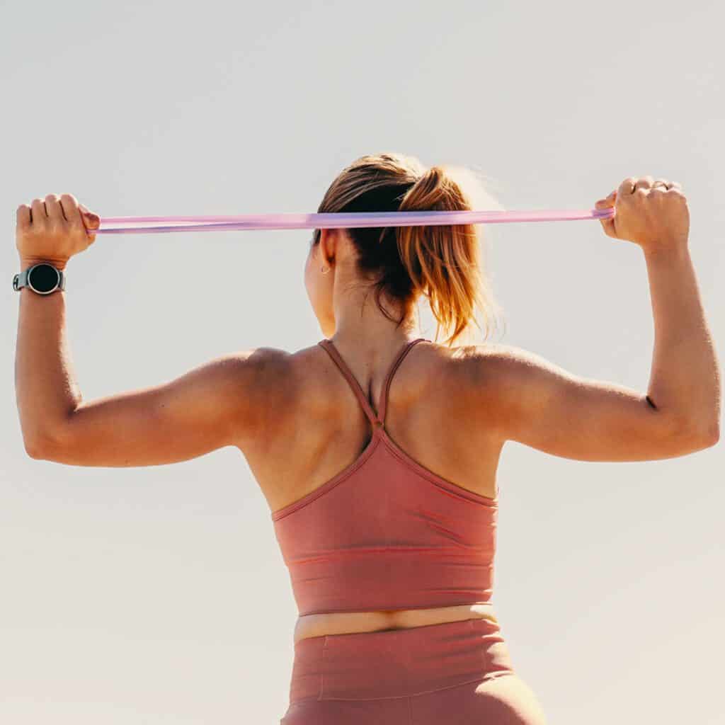 athletic woman doing shoulder workouts with resistance band