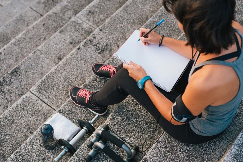 woman writing her fitness goals in her fitness journal
