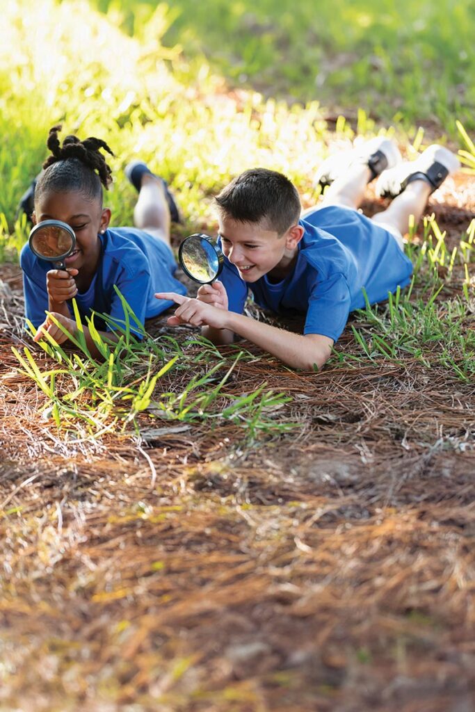 Kids watching ants with magnifying glasses