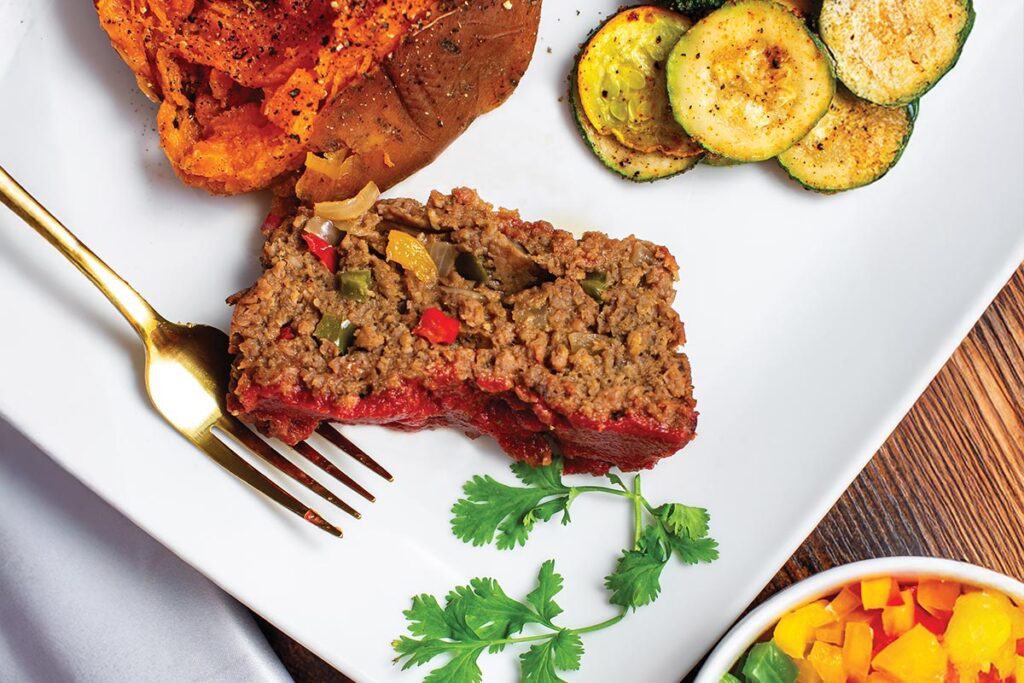 meatloaf on a plate with a sweet potato and zucchini