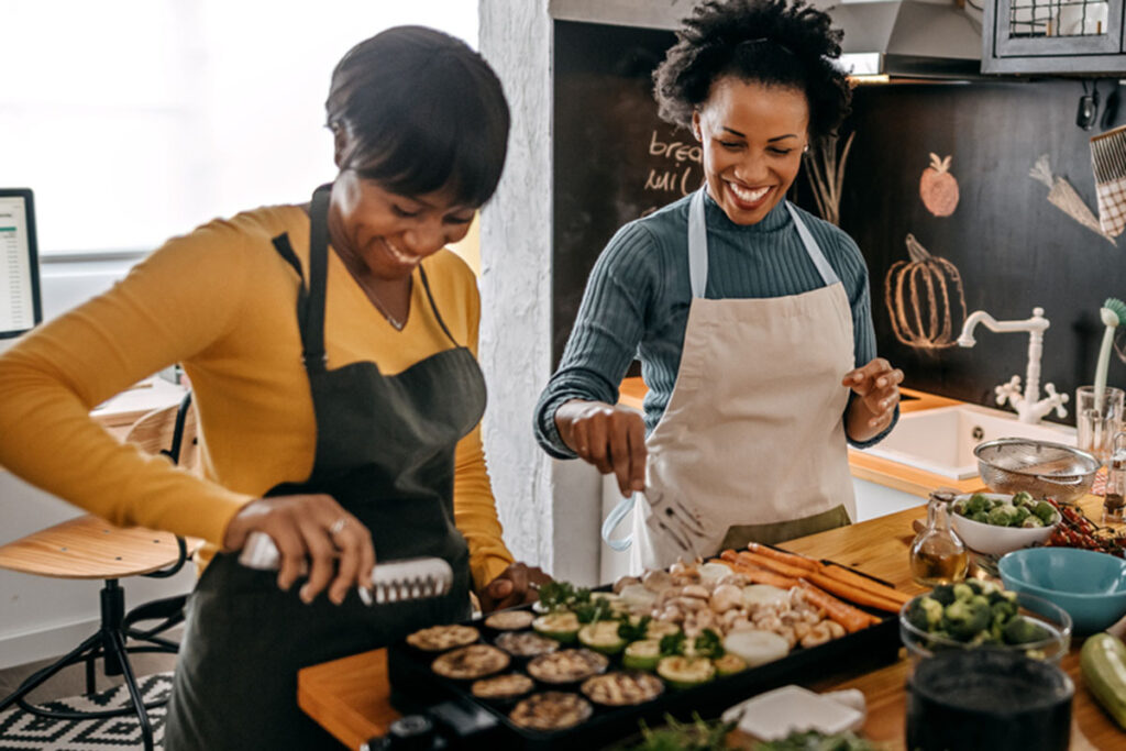 Three female friends cooking food in kitchen