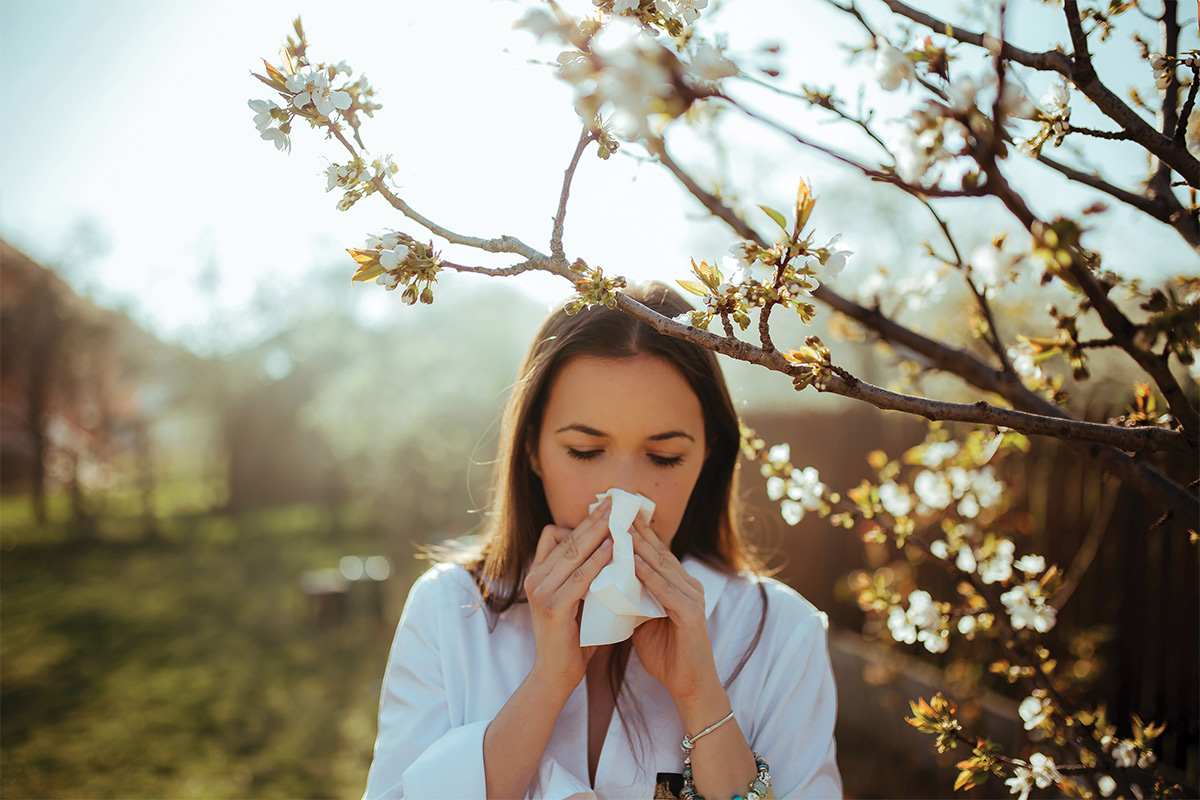 Woman sneezing outside in the springtime