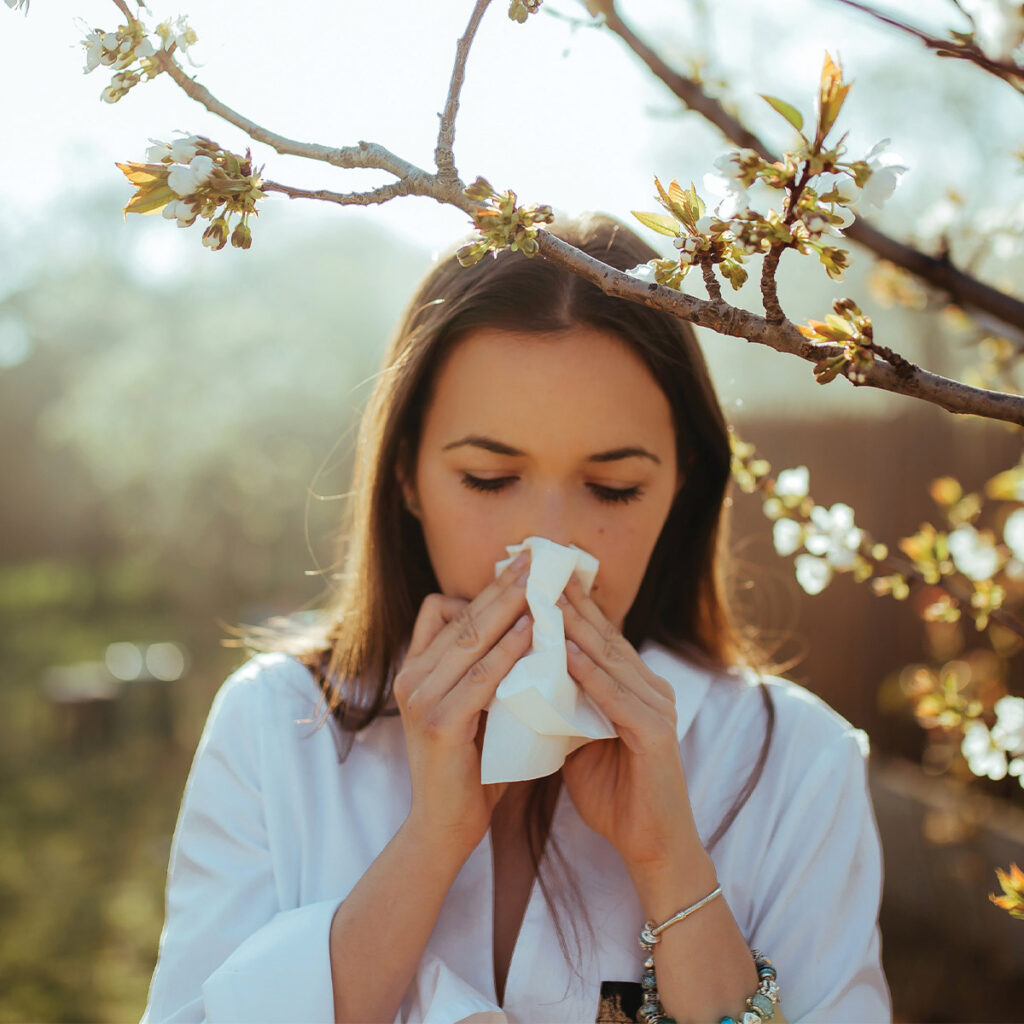 Woman sneezing outside in the springtime