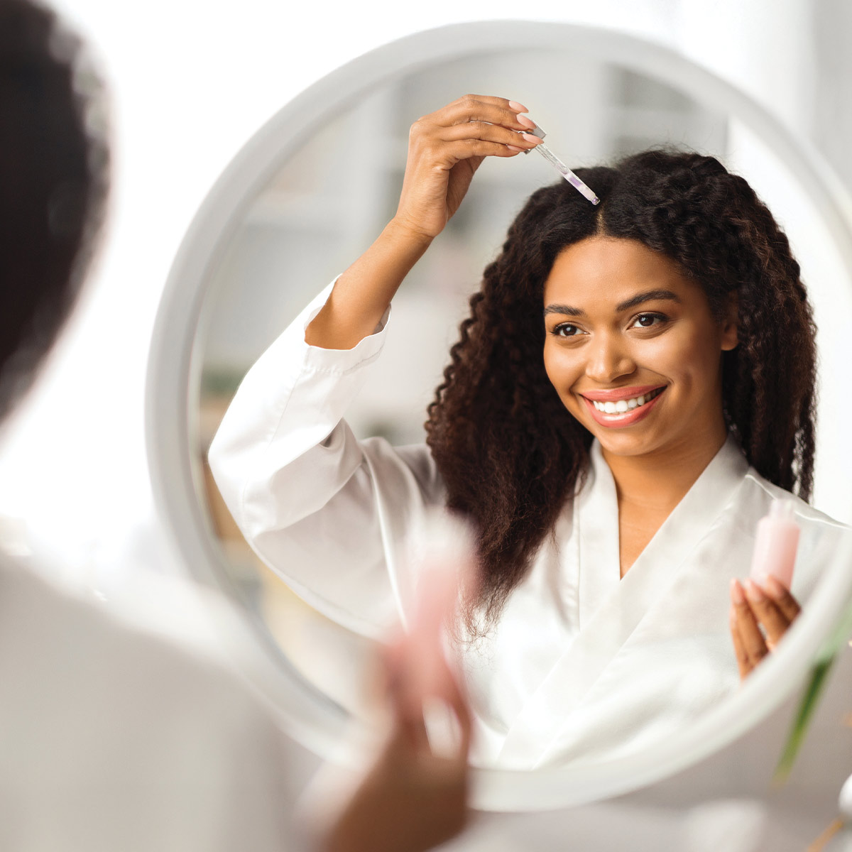 woman applying hair oil to her scalp