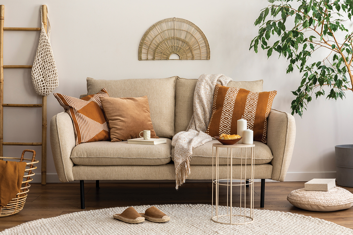 Cozy living room with a beige sofa adorned with orange pillows, a throw blanket, and natural decor elements.