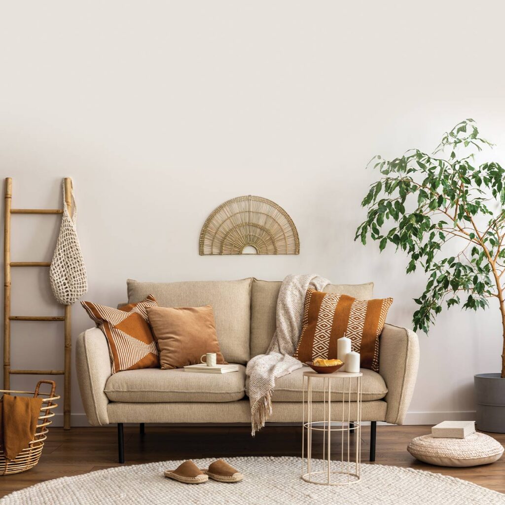 Cozy living room with a beige sofa adorned with orange pillows, a throw blanket, and natural decor elements.