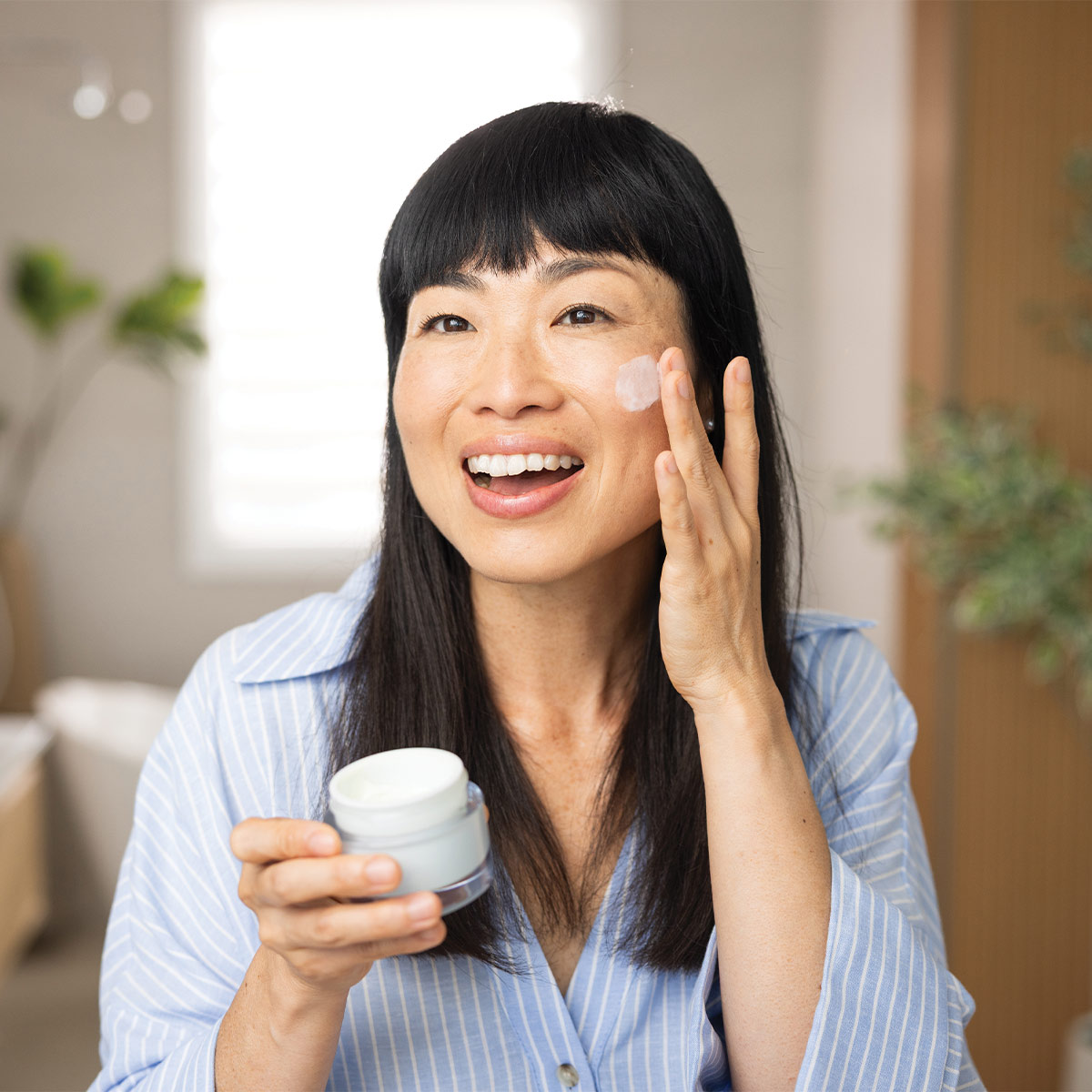 older woman applying moisturizer to her face