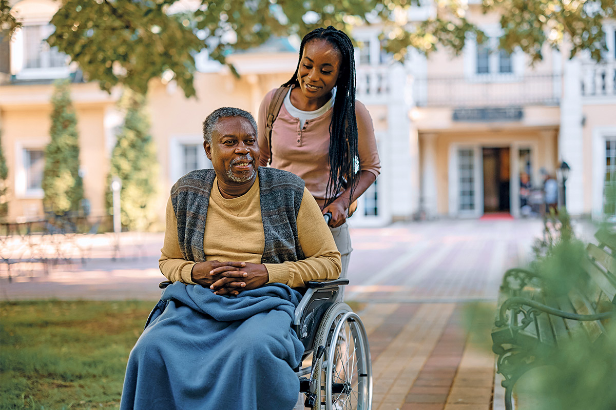 daughter pushing aging father in wheelchair