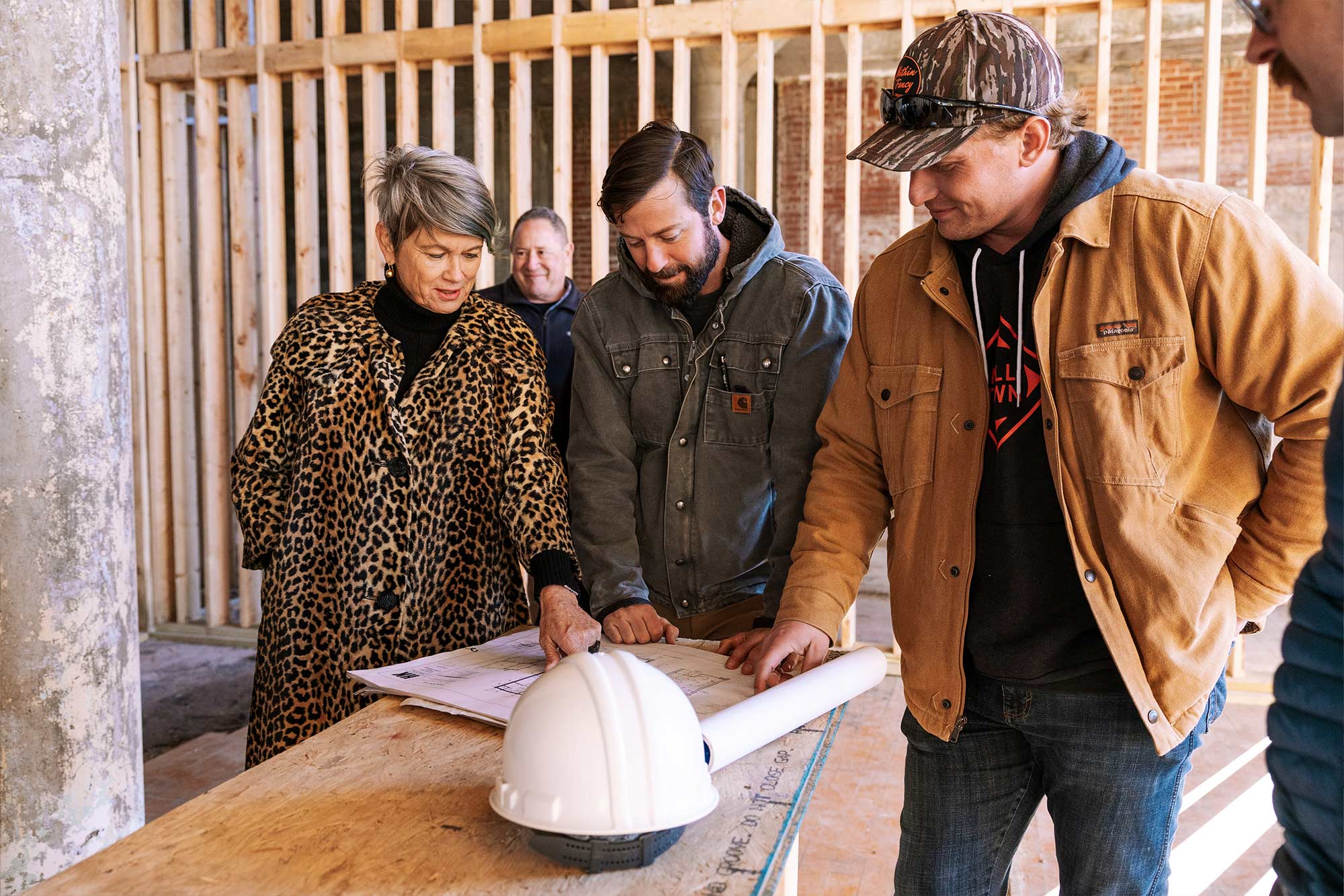 Group of people talking around blueprints with construction in the background