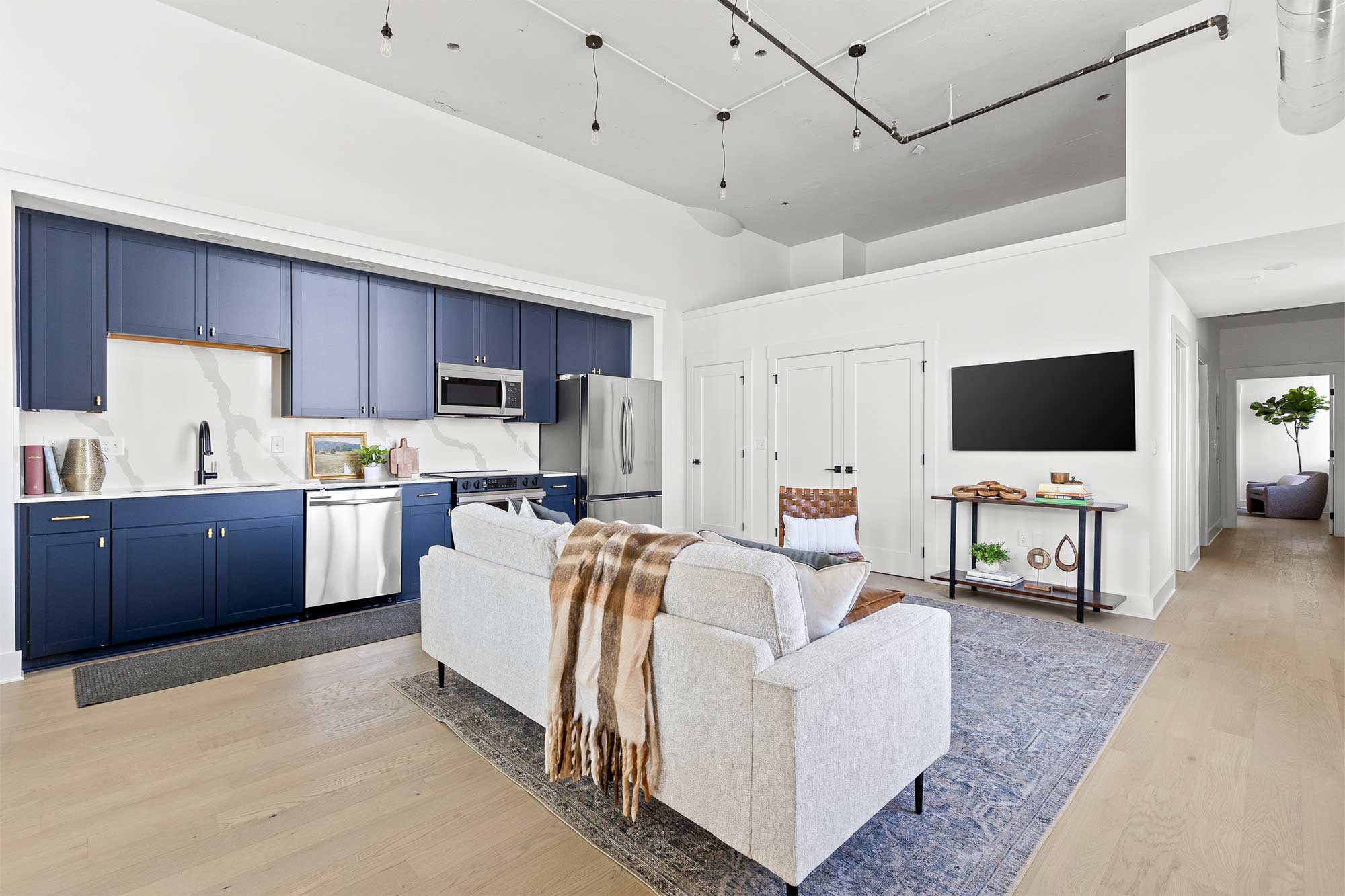 Beautiful open concept living room and kitchen with blue cabinets and white walls