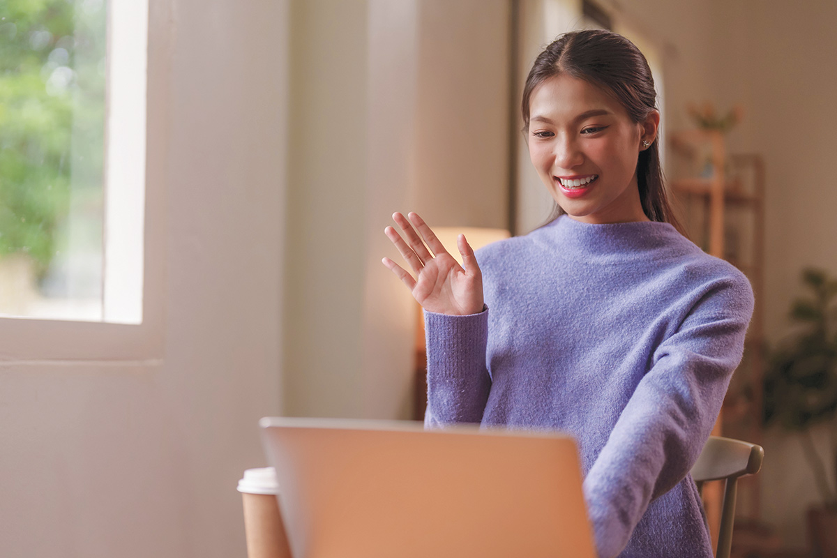 Woman waving at computer screen for therapy