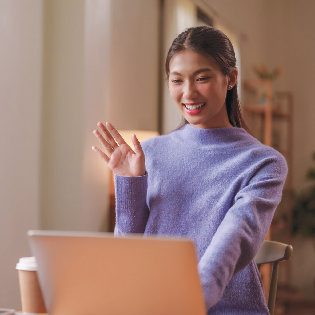 Woman waving at computer screen for therapy