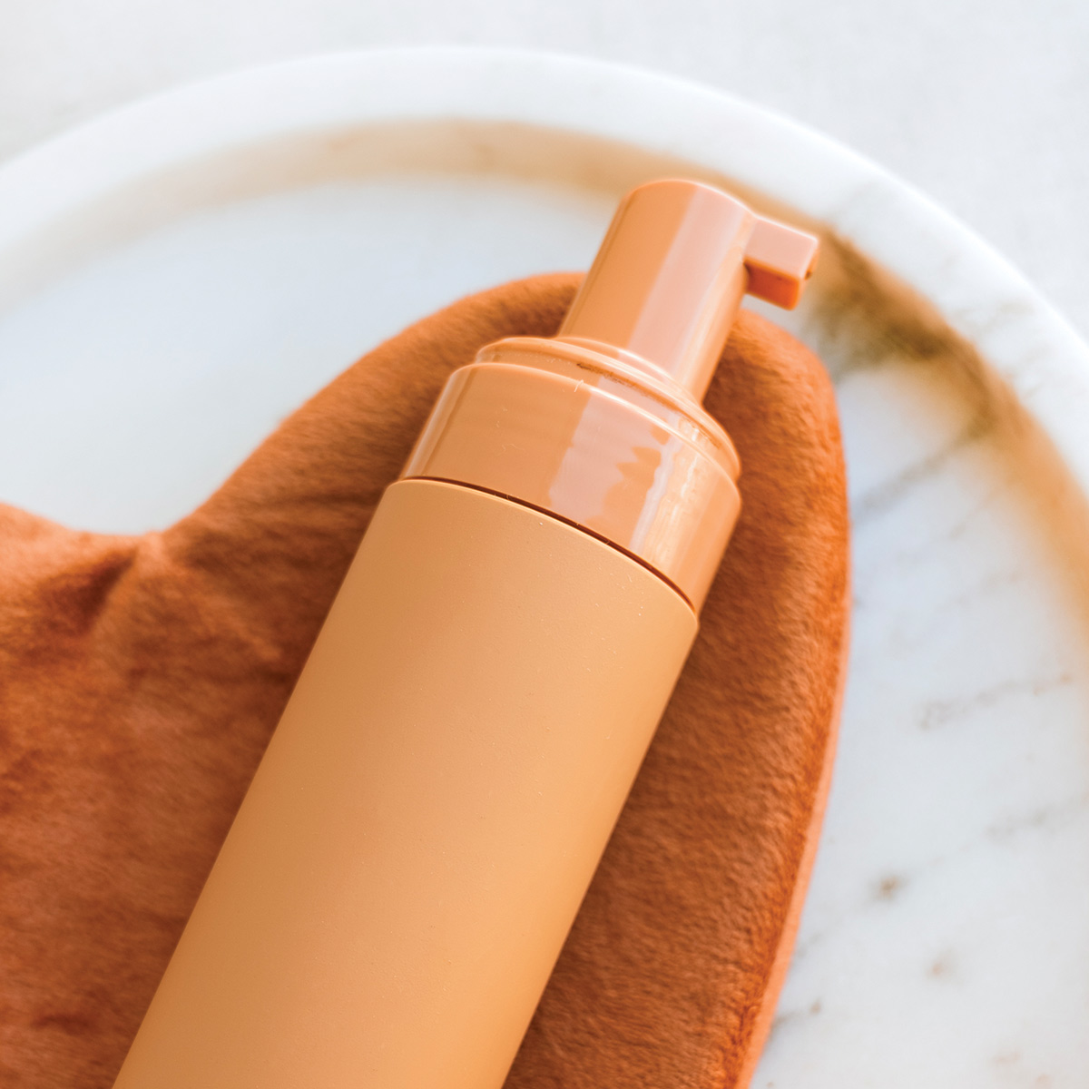 orange self tanner bottle and mitt