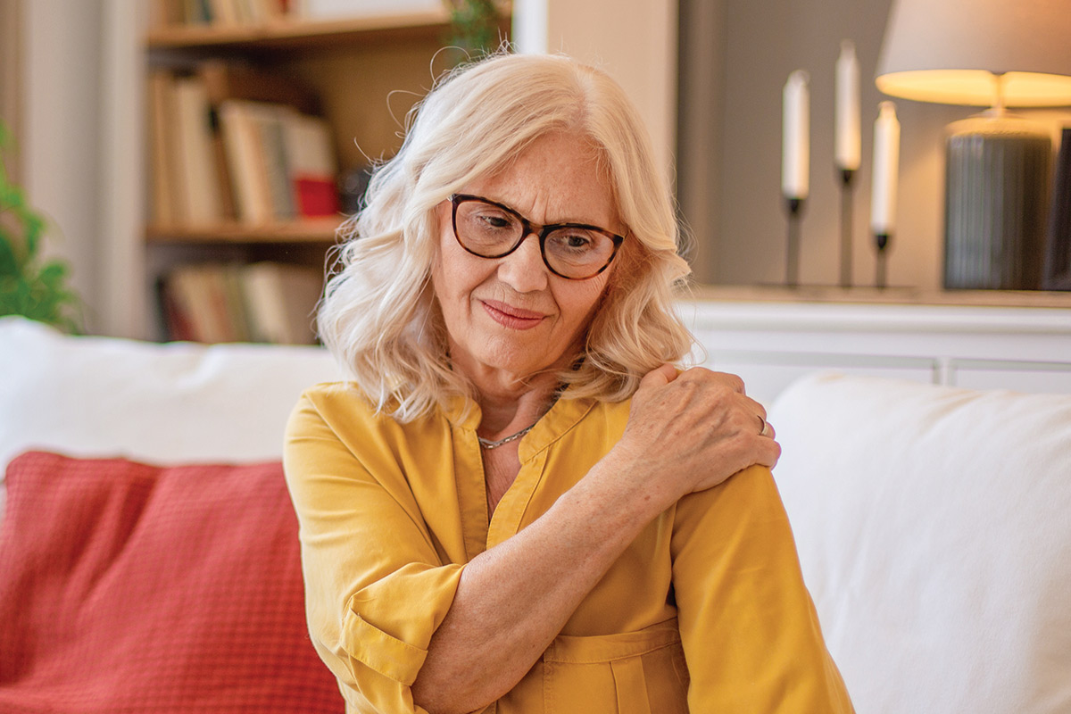 mature woman holding shoulder in pain