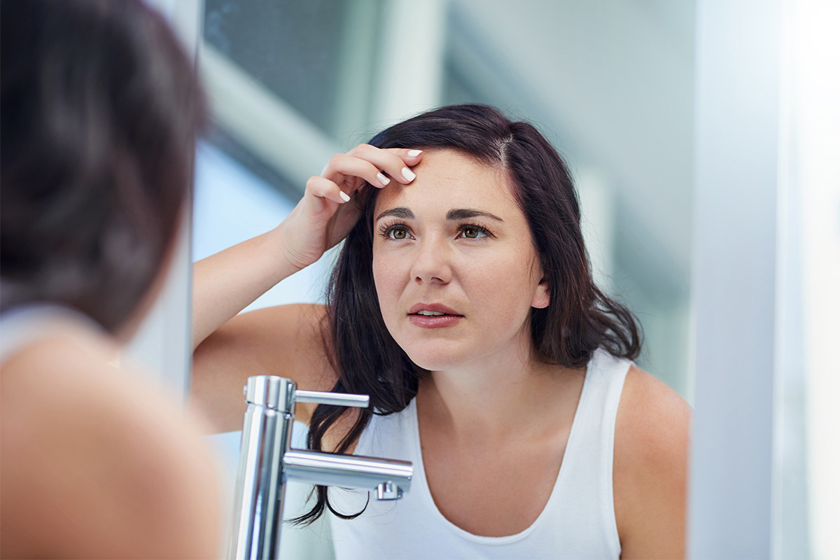 woman examining her skin in the mirror