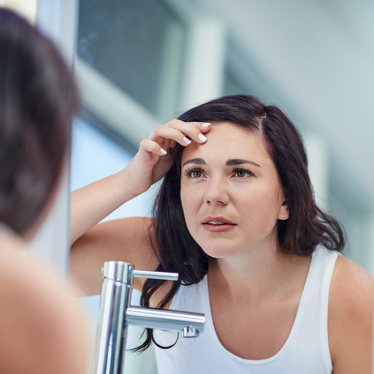Woman checking her skin in the mirror
