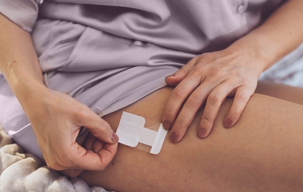 woman applying a medicine patch to her outer leg